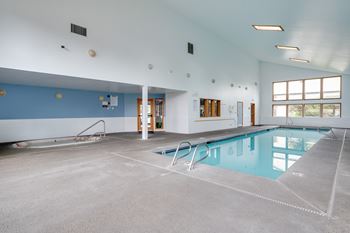 a large indoor swimming pool with a concrete floor and blue walls